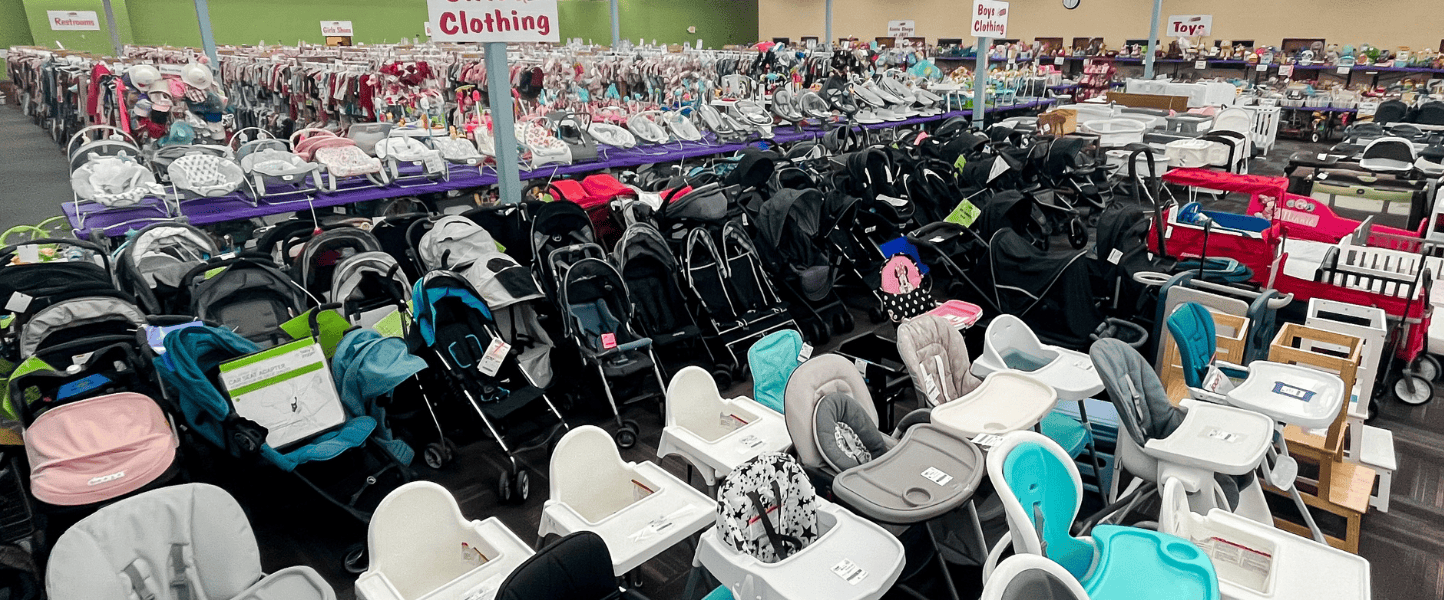 A mom and her child hug in between two rows of little girl clothes